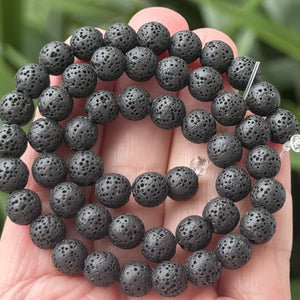 Black lava diffuser beads on a 15.5 inch strand; natural volcanic lava, dyed black and waxed, 6.5–10.5 mm, 2 mm hole.